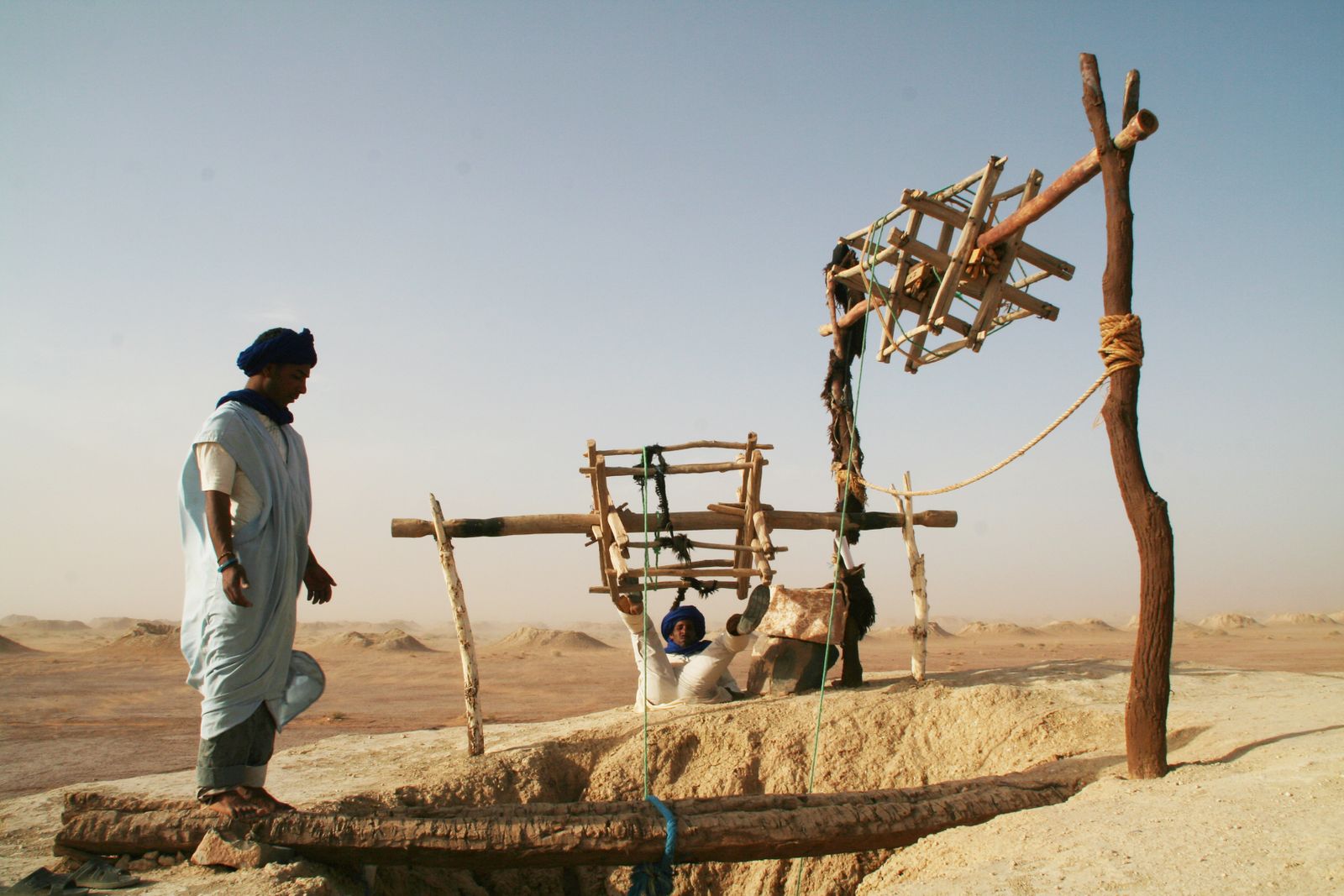A hand-dug well with a wooden hoist standing in dry open country
